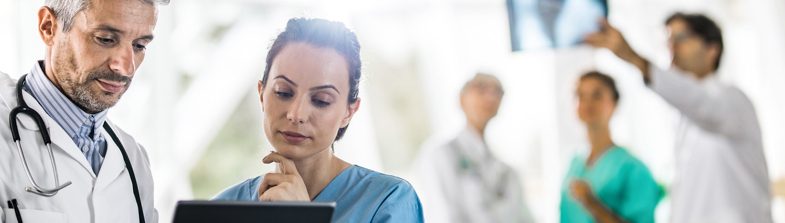 Ärztliches Fachpersonal überprüft Patientendaten auf einem Tablet.