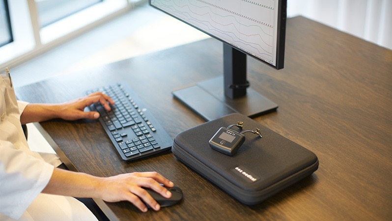 Medizinische Fachkraft wertet mit einem Diagnostikgerät Schlafdaten am Computer aus.