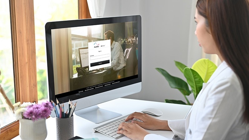 Frau sitzt vor einem Computer und nutzt das AirView™-Telemonitoring-Portal von ResMed.