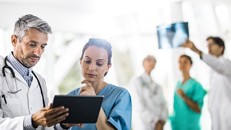 Ärztliches Fachpersonal überprüft Patientendaten auf einem Tablet.