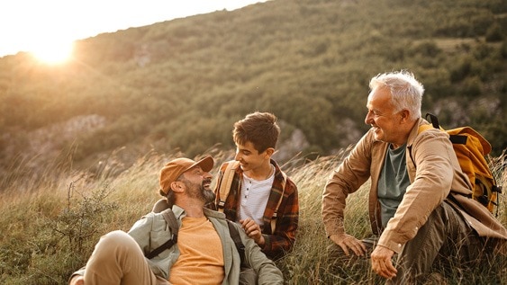 Drei Generationen von Männern genießen eine Wanderpause im Sonnenuntergang