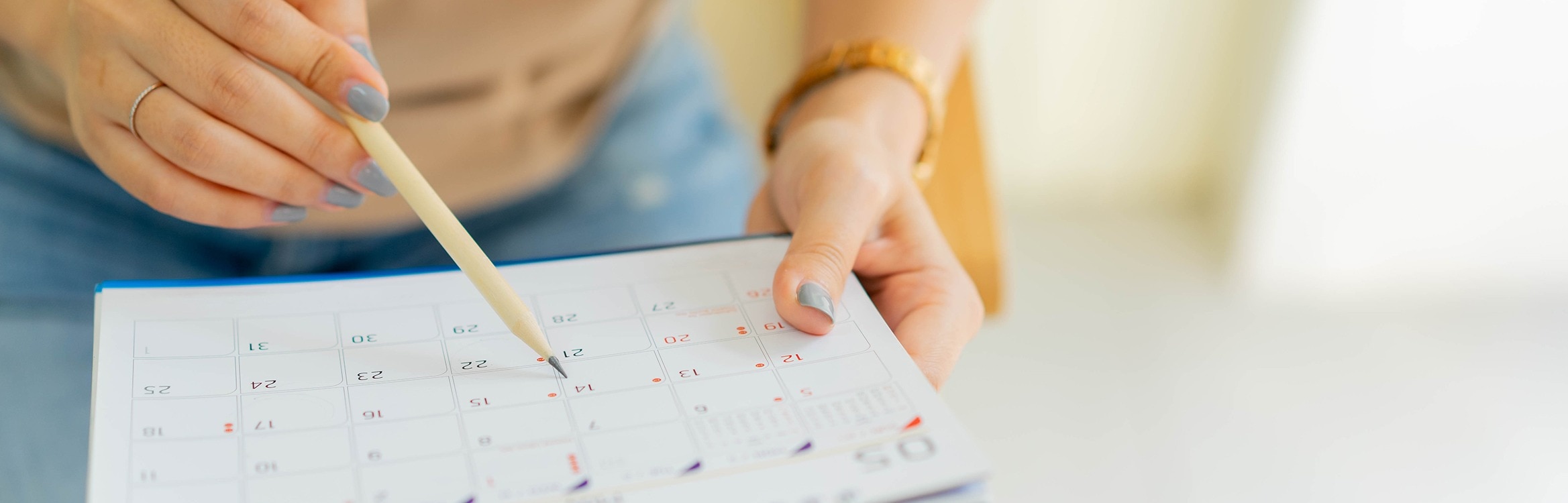 Hände mit Kalender und Bleistift für Terminplanung.