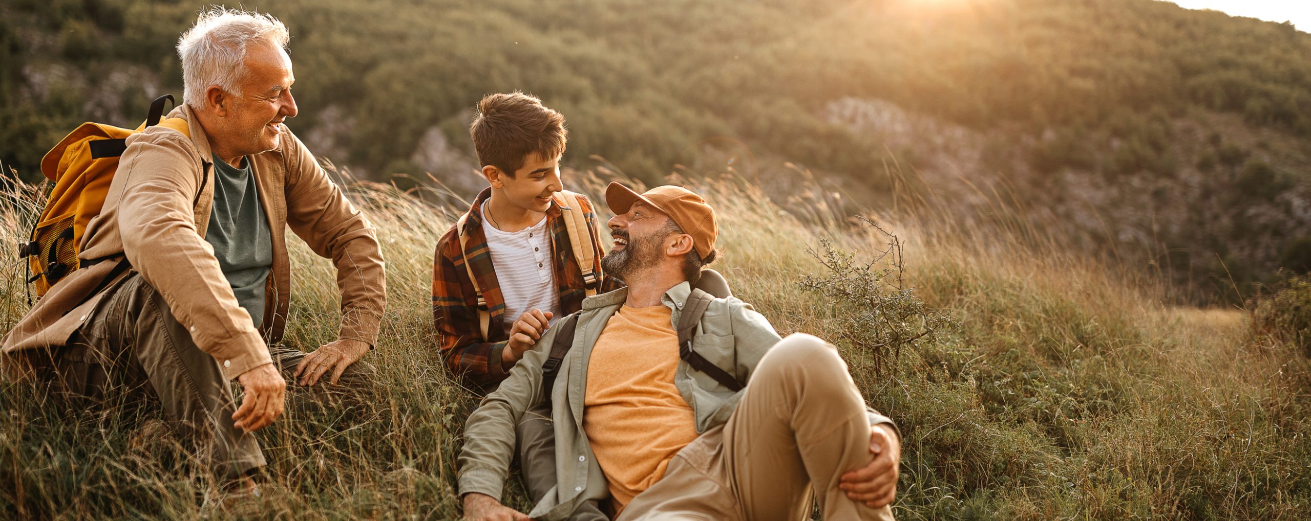 Drei Generationen von Männern genießen eine Wanderpause im Sonnenuntergang