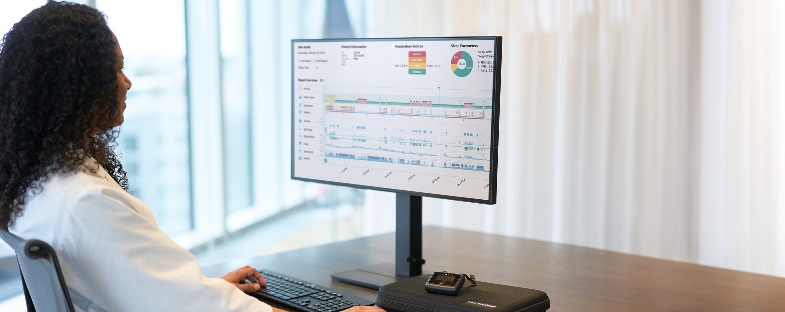 Ärztin analysiert Schlafdaten eines Patienten auf einem Monitor.