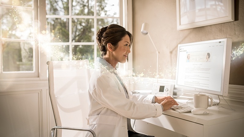 Ärztin sitzt an einem Schreibtisch und arbeitet am Computer, um moderne Versorgungskonzepte zu überwachen.